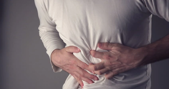 persoana care se tine de partea dreapta a abdomenului din cauza unei crize de fiere