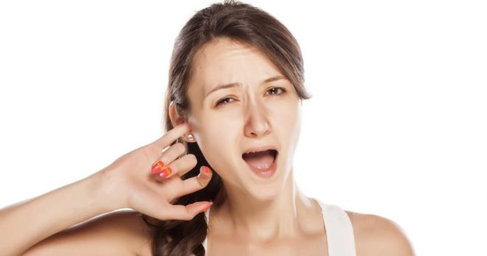 femeie care tine un deget in ureche din cauza mancarimii de care sufera