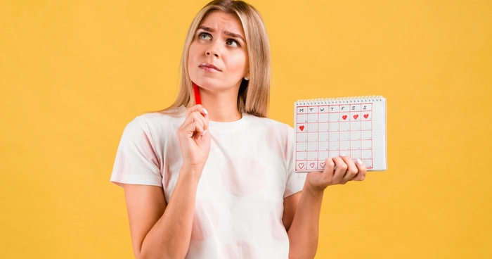 femeie care tine un calendar in mana si se gandeste
