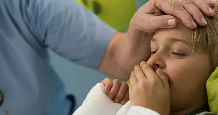 medic care tine mana pe capul unui baietel care sufera de tuse latratoare