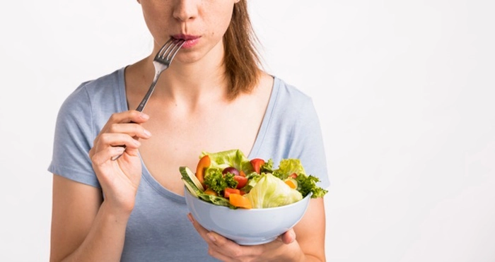 femeie care tine un bol cu salata in mana si mananca din ea