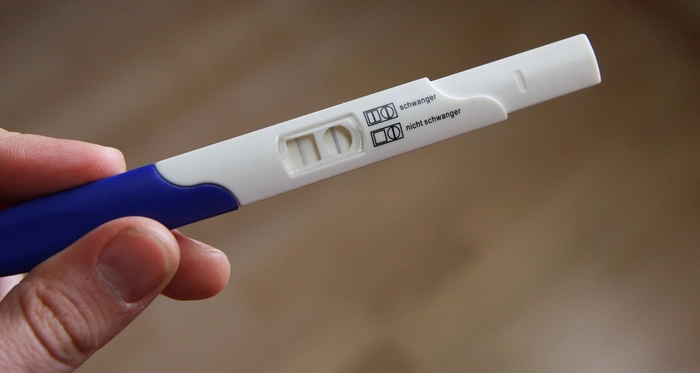 femeie care tine in mana un test de sarcoma pozitiv