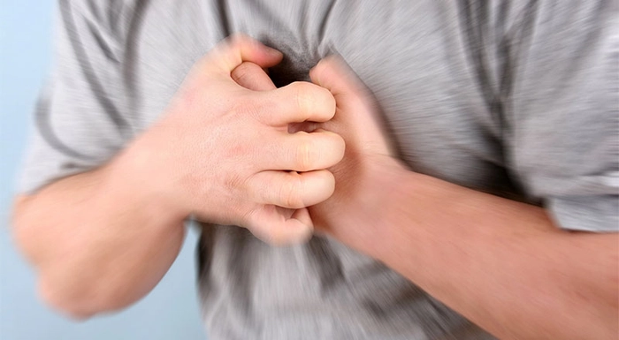 persoana care se tine de piept din cauza durerii provocate de inima