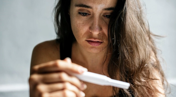 femeie care priveste un test de sarcina