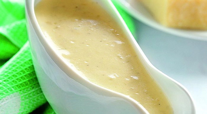 un recipient cu sos alfredo langa un prosop verde