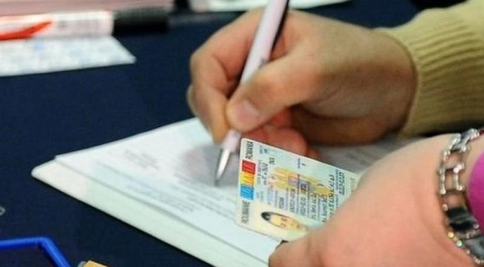  O persoana tine in mana un buletin si completeaza un act