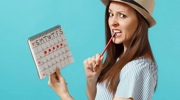 femeie care tine un calendar in mana si un creion in gura