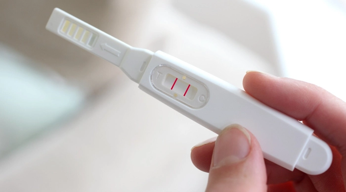 femeie care tine in mana un test de sarcina