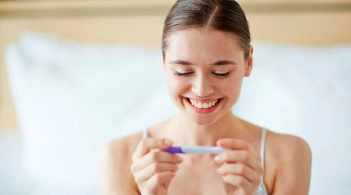 femeie care tine in mana un test de sarcina