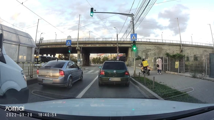 un tanar de la glovo ce asteapta sa treaca de pe trotuar pe carosabil