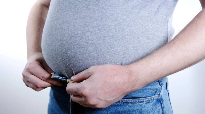 barbat care se tine de pantaloni si are o burta foarte umflata