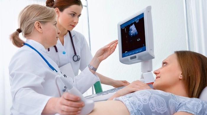 femeie insarcinata la un control la ecograf langa doi medici