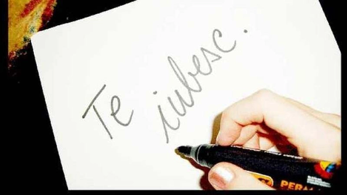 persoana care scrie te iubesc pe o hartie
