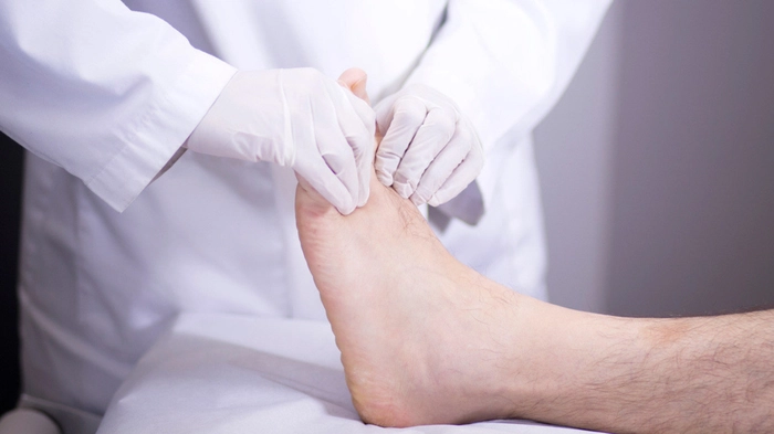 medic care examineaza piciorul unei persoane