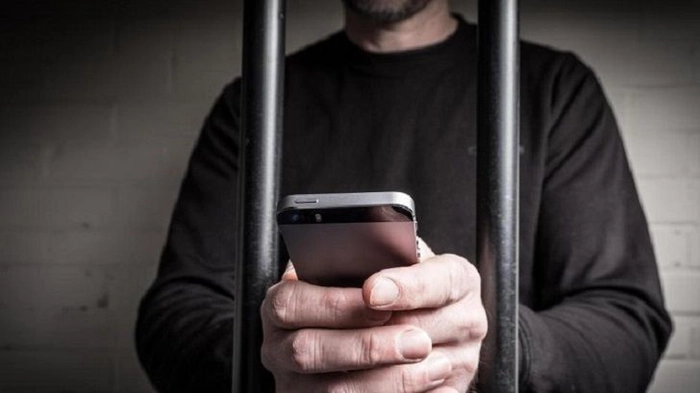 un barbat care foloseste telefonul intre bare