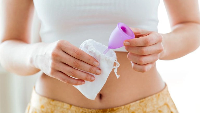 femeie care scoate dintr-un saculet o cupa menstruala