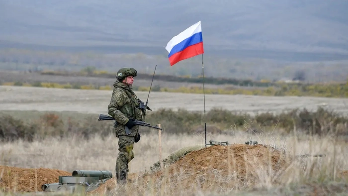 soldat rus echipat care sta pe camp cu un flag