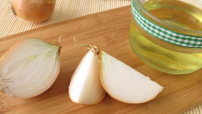 mai multe bucati de ceapa langa un recipient cu suc de ceapa