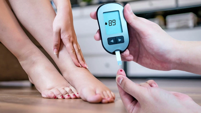 colaj persoana care se tine de picioare si alta persoana care isi verifica nivelul de glicemie din sange