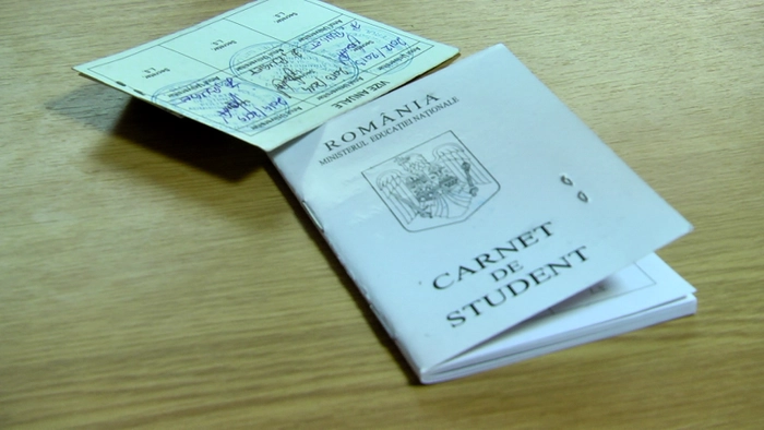  un carnet de student si o legitimatie de transport, asezate pe o baza din lemn