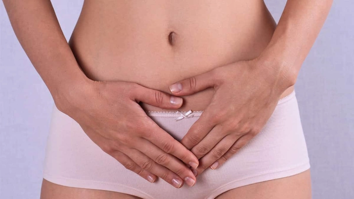 o femeie în lenjerie intimă care ține mâinile pe abdomen