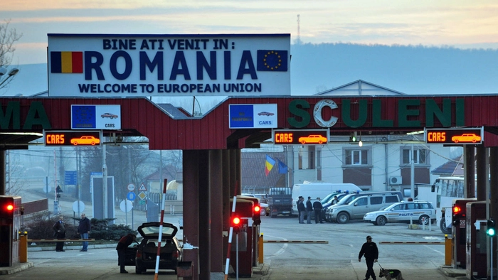 Imagine de ansamblu cu Vama Sculeni, diverse autoturisme in fundal, un om cu o valiza