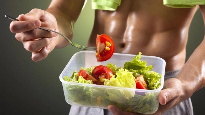 barbat care tine un bol cu salata in mana si o furculita