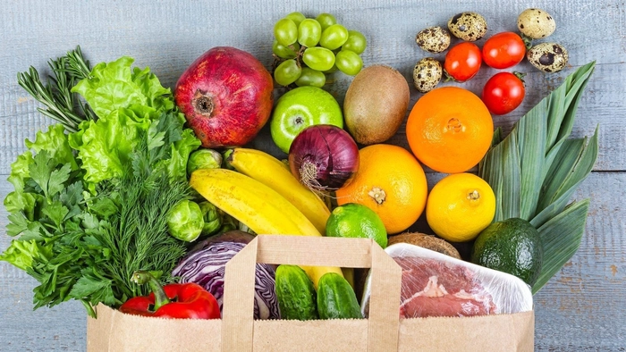 o punga de hartie din care ies mai multe fructe si legume