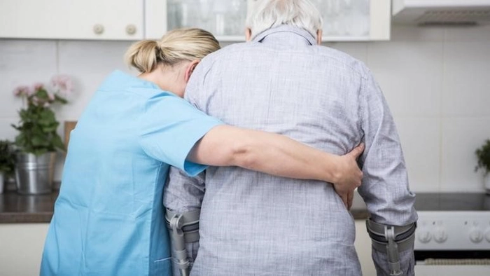 o asistentă medicala care il ajuta sa mearga pe un batran