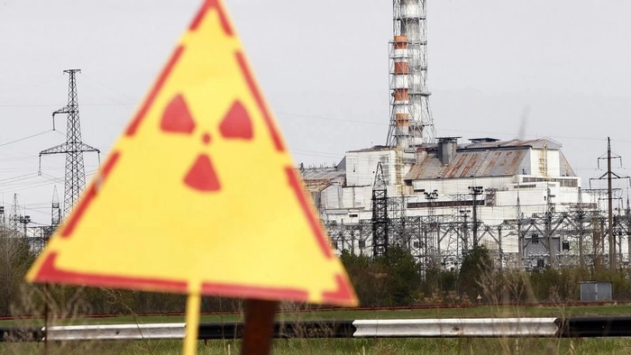colaj foto semn de “atentie radioactiv” si o centrala nucleara pe fundal