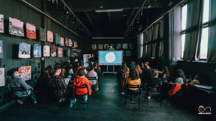 mai multe persoane intr-o sala de worshop