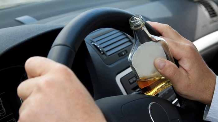 un barbat cu o sticla cu alcool in mana