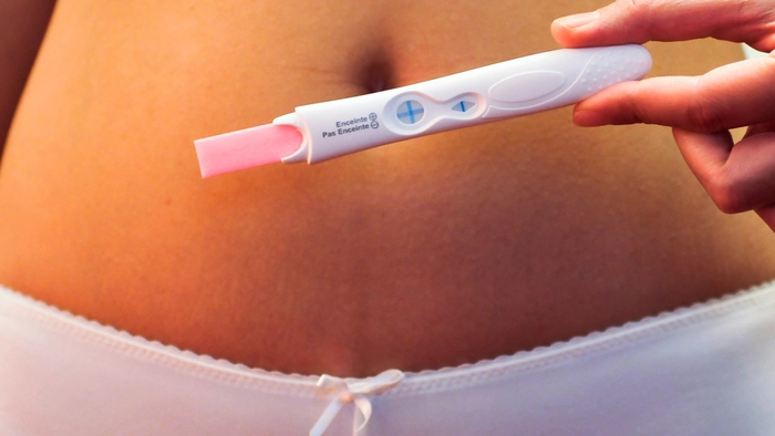 femeie care tine un test de sarcina in mana