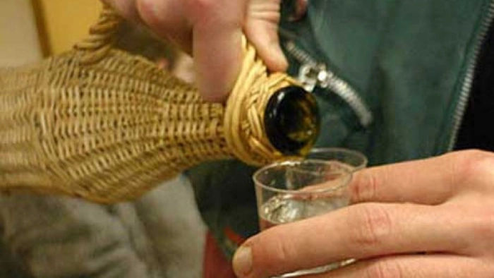 un bărbat care toarnă țuică ăntr-un pahar