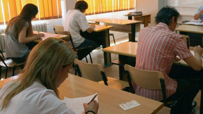  persoane care stau in banci si sustin un examen