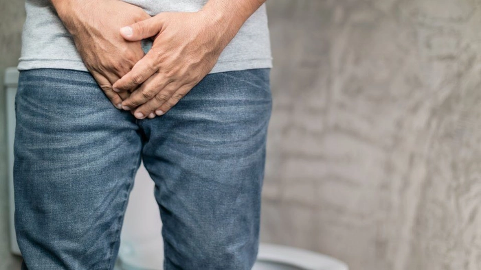 barbat care se tine de testicul din cauza urinarii greoaie