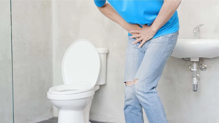 barbat care se tine de testicul din cauza urinarii greoaie intr-un viceu