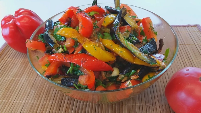zacusca de vinete cu ardei si alte ingrediente intr-un bol pe o masa langa alti ardei proapeti