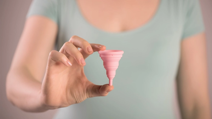 femeie care tine in mana o cupa menstruala
