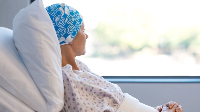 femeie bolnava de cancer care priveste pe geam