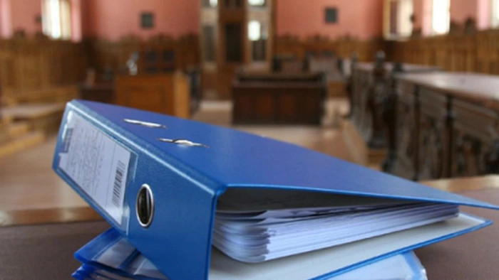 o persoana arata cu degetul iar o alta semneaza un contract pe o masa