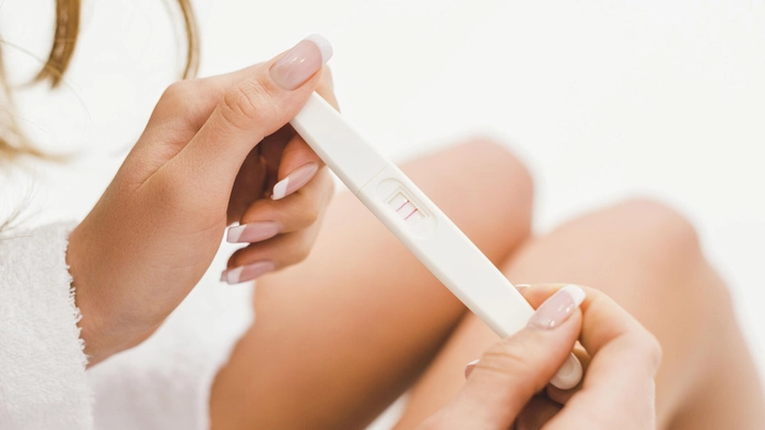 femeie care tine un test de sarcina pozitiv in mana
