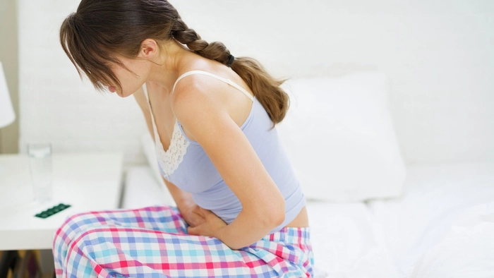 femeie care se tine de partea stanga a abdomenului