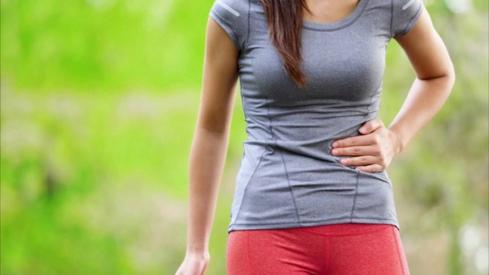 femeie care se tine de partea stanga a abdomenului