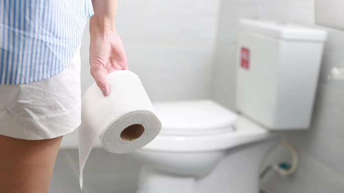 barbat care tine in mana o hartie igienica langa tualeta