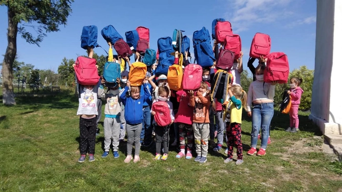 o poză cu niște copilașii care au primit ghiozdane