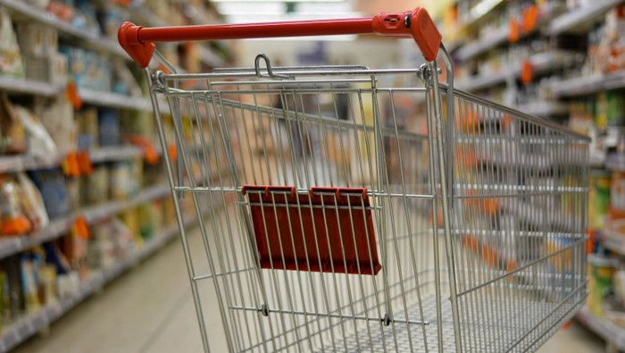 un carucior de cumparaturi gol aflat printre rafturile unui magazin