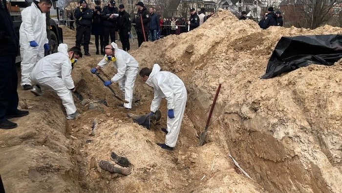 în urma masacrului de la Bucea, anchetatori ce sapa intr-o groapa comuna