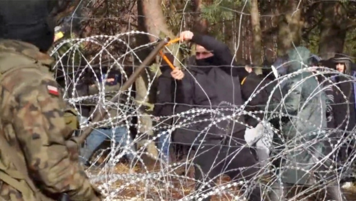 tensiuni între grăniceri, granita dintre Polonia si Belarus, barbat ce incearca sa taie sarma ghimpata de la granita