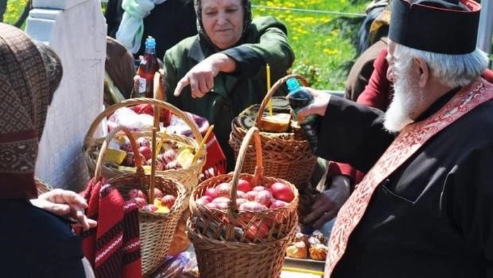 o imagine cu un preot care uda cu vin cosurile cu pomana